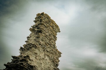 Ancient stone tower ruins against a cloudy sky.