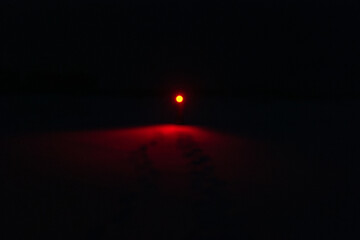 A Person in the Snow Shining a Creepy Red Flashlight in the Dark Night