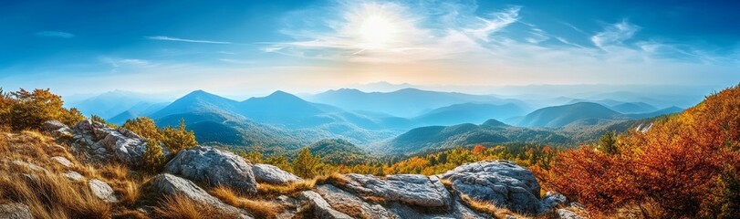 Obraz premium Panoramic view of a mountain range with a blue sky and clouds. The mountains are covered in trees, and there is a rocky outcropping in the foreground.