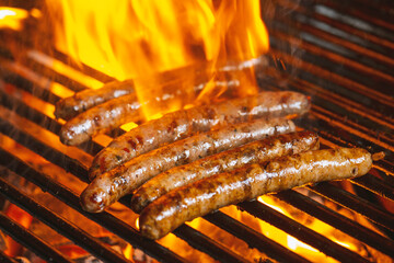 Grilling sausages on the grill with flames and smoke.
