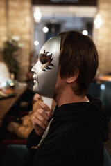 A man sits on a chair with a mask on his face. Mafia game. Entertainment and relaxation in the company of people.