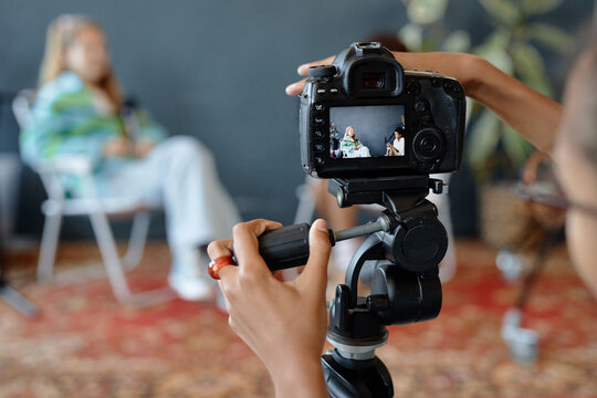 Close up of teenage kid setting up camera on tripod in studio and working with equipment settings at digital screen, copy space