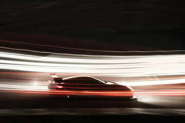 An artistic image of a sports car in motion showcases blurred light trails, emphasizing speed and performance against a dark background for sports.