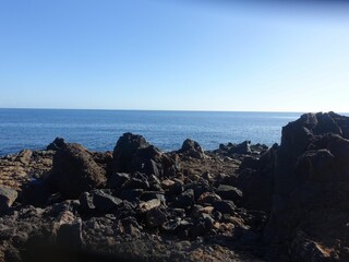 Rocky coastline with clear blue sea and sky.