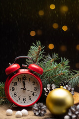 Red retro alarm clock with fir branches and a Christmas tree toy. The clock shows a few minutes...