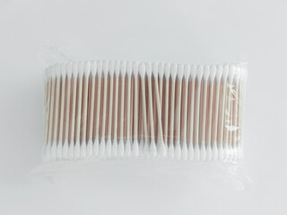 Bamboo brown cotton swabs in transparent packaging on white background. Top view.