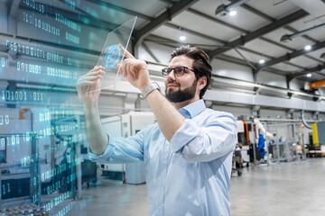 Smiling engineer using transparent tablet PC for binary codes in factory