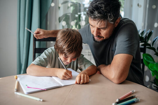 Father assisting son doing homework at home