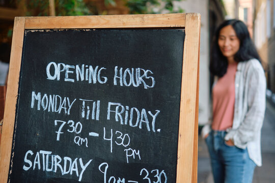 Open sign board with text near owner standing in background