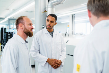 Team of competent electrical technicians in lab coats having meeting in electronics factory