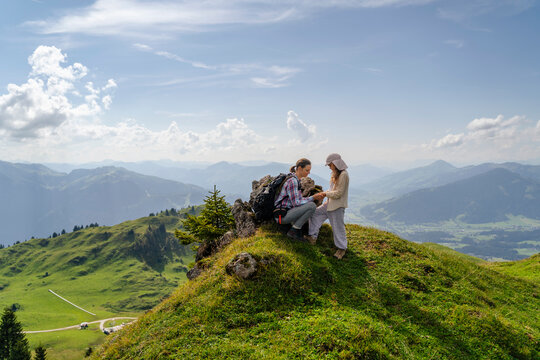 Mother and daughter spending leisure time on mountain under cloudy sky