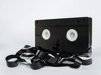 Video cassette turned back with chaotically unwound magnetic tape in the foreground isolated on...