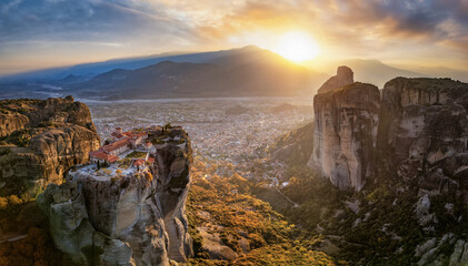 Aerial sunset view of the Meteora mountains with Agia Triada monastery and the town of Kalabaka in the valley behind, Greece