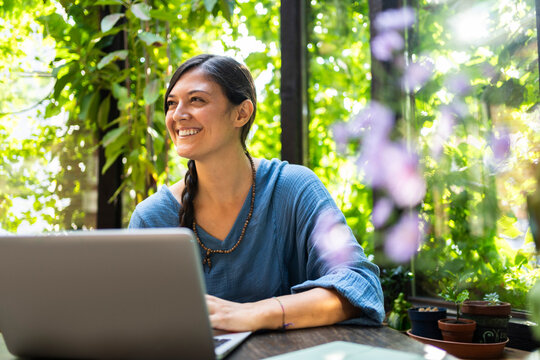 Happy freelancer sitting with laptop in gazebo