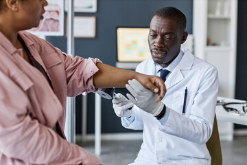Portrait of adult African American man as doctor examining patient during consultation in clinic...