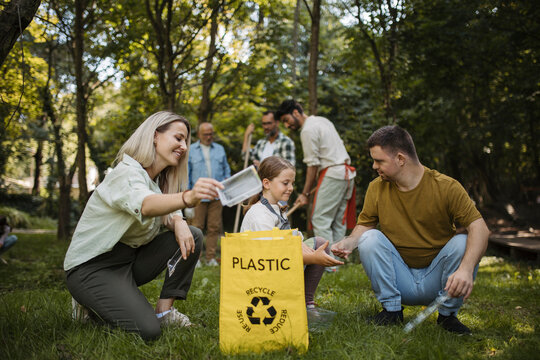 Socially inclusive group of volunteers putting plastic waste in recycling bag