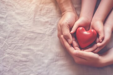 Obraz premium Hands of family members gently cradle a vibrant red heart, symbolizing their commitment to heart health and community support during awareness campaigns.