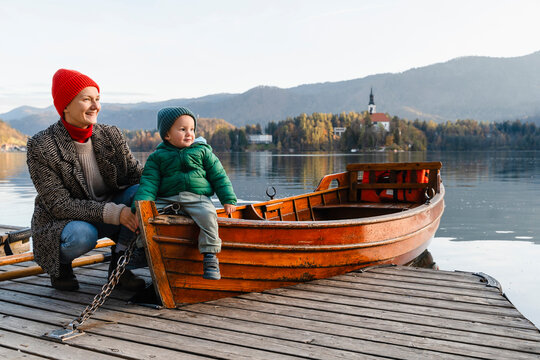 Smiling mother and son sitting on boat at lakeshore