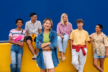 Confident young woman standing in front of group of friends with arms crossed