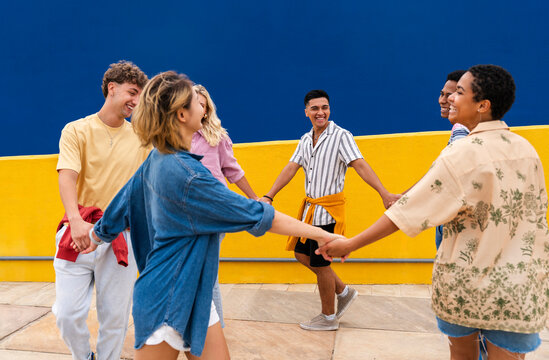 Multi-ethnic group of friends holding hands dancing in a circle