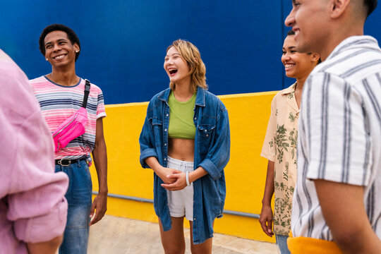 Cheerful friends chatting next to colorful wall