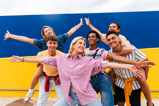 Group of young friends with colorful clothing posing happily in front of wall