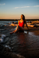 A girl in a red swimsuit lies on the beach at sunset