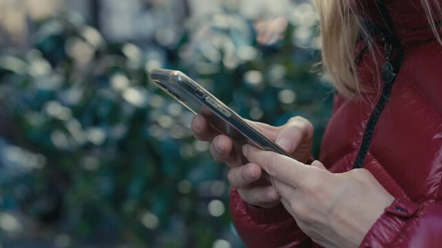 Woman using a mobile phone. Phobia of not having a mobile phone. Strong anxiety if there is no mobile phone at hand. A close-up of a person holding a smartphone in a vibrant city setting, capturing