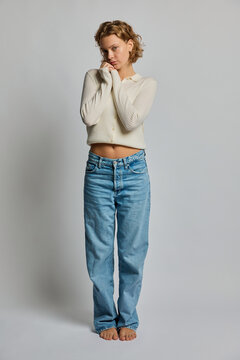 Innocent young woman hugging self against white background