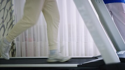 Close-up footage of a person running on a treadmill as part of a rehabilitation session indoors, focusing on controlled movement and recovery. Concept of physiotherapy and physical rehabilitation