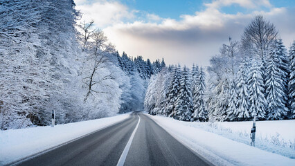Obraz premium In a winter landscape in Germany, a road covered in snow and trees covered in snow.