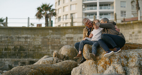 Grandparents, grandchild and relax on rocks at beach for family holiday, happy memory and travel...