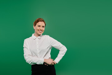 A professional woman in a smart white shirt stands confidently with a friendly smile on a green backdrop.