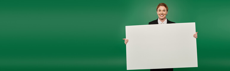 The TV presenter in a formal black outfit smiles, ready for a broadcast against a vibrant green...