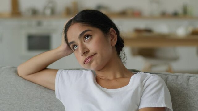 Close up boring sad upset frustrated thinking suffer disappointed bored think pensive thoughtful Hindu woman Indian girl Arabian female lady at home couch problem at sofa confused puzzled hesitate