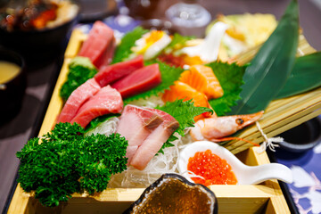 A vibrant platter of fresh sashimi served on ice, featuring salmon, tuna, shrimp, and fish roe, garnished with leafy greens and presented in a wooden tray, embodying Japanese cuisine's artistry.