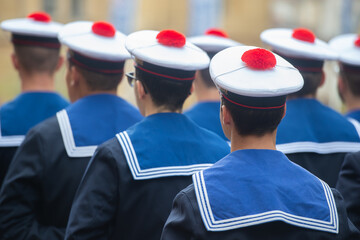 Les soldats de la Marine Nationale française, en tenue et en uniforme, avec leur chapeau à pompon rouge , vue de dos lors d'un défilé militaire. 