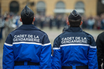 deux cadets de la gendarmerie vus de dos avec ll'inscription sur la veste bleue , ils ont les 