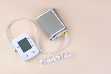 Digital blood pressure tonometer and pack of pills on a light background with copy space.