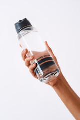 Person, hand and water bottle in studio for hydration, nutrition and refreshing mineral liquid....
