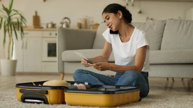 Hindu woman Indian girl Arabian female at home prepare for trip vacation travel talking call talk smartphone mobile phone packing clothes in suitcase baggage holding tickets airline airport passport