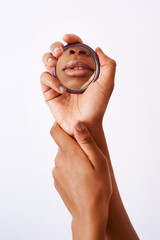 Naklejka premium Hands, African woman and mirror for lips or cosmetics on studio background as makeup artist. Female person, beauty and reflection as aesthetic in skincare, wellness and dermatology for natural glow