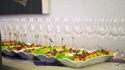 A chef inserts skewers into a row of neatly arranged appetizer dishes on a buffet table.