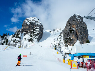 Olympic downhill ski run Olimpia 1 in Cortina d’Ampezzo in Dolomites, Italy. The steepest part between big rocks. Ski lift and unrecognizable skiers. Slope often used for Alpine ski World Cup races