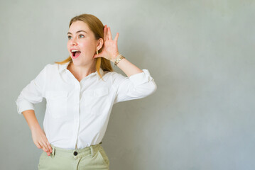 Surprised young professional woman listening intently with her hand to her ear