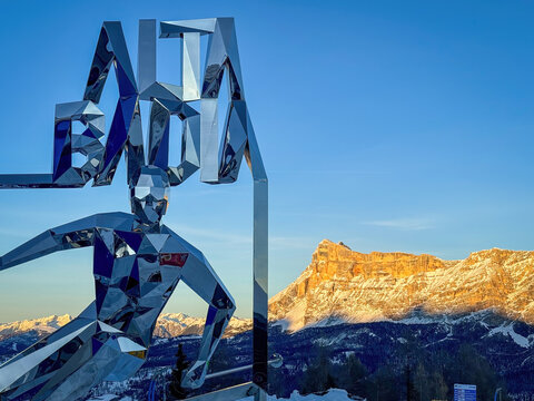 Alta Badia, Italy - December 17, 2023: Gigant Alta Badia Sculpture Statue of Skier at Piz la Ila against Heiligkreuzkofel mountain and blue sky at sunset