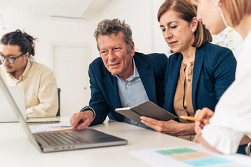 Professional business team discussing project strategy senior executive manager leading diverse group meeting in modern office