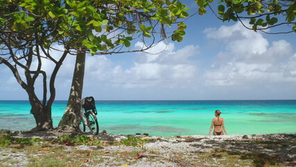 Tourist is enjoying a well-deserved rest on a pristine beach after a bike ride, surrounded by the breathtaking beauty of rangiroa island in french polynesia