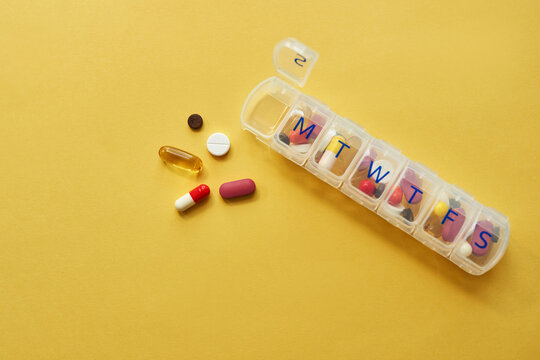 Drugs, medicine and daily container in studio for healthcare routine, medical reminder and prescription. Pills, collection and tablets storage, management and treatment schedule on yellow background