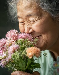 Naklejka premium An elderly woman smiles joyfully while inhaling the sweet aroma of fresh flowers in her hands